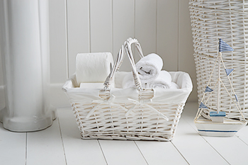 White basket for toilet rolls. towels and toiletries