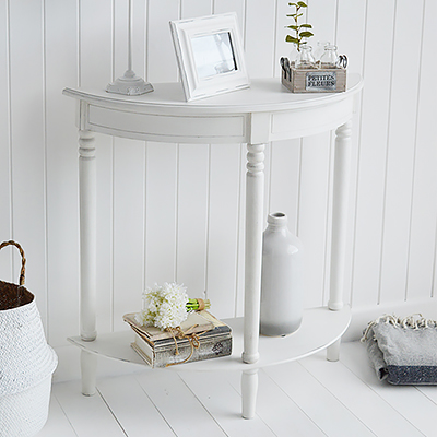 Colonial half moon white console table with a shelf, a typical white piece of coastal furniture for a living room