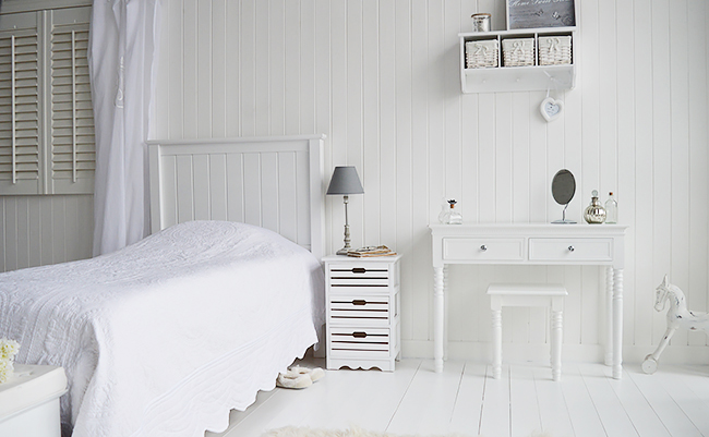 Photograph of white bedroom with dresser, bedside and accessories
