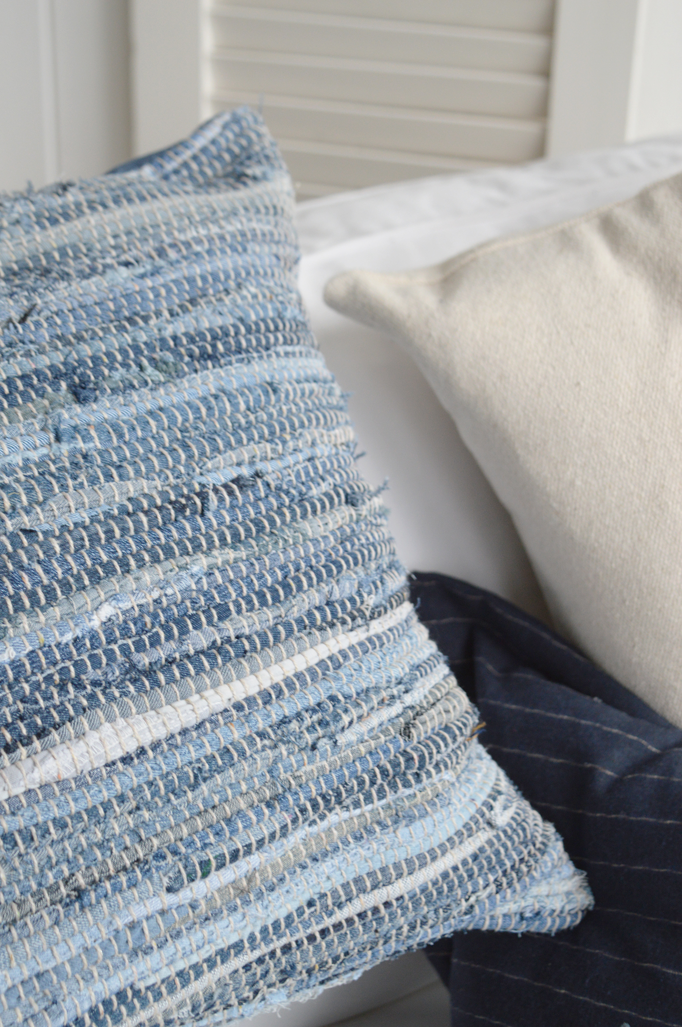 Handwoven blue and white textured cushion styled with cream and navy pillows in Hamptons coastal interior setting