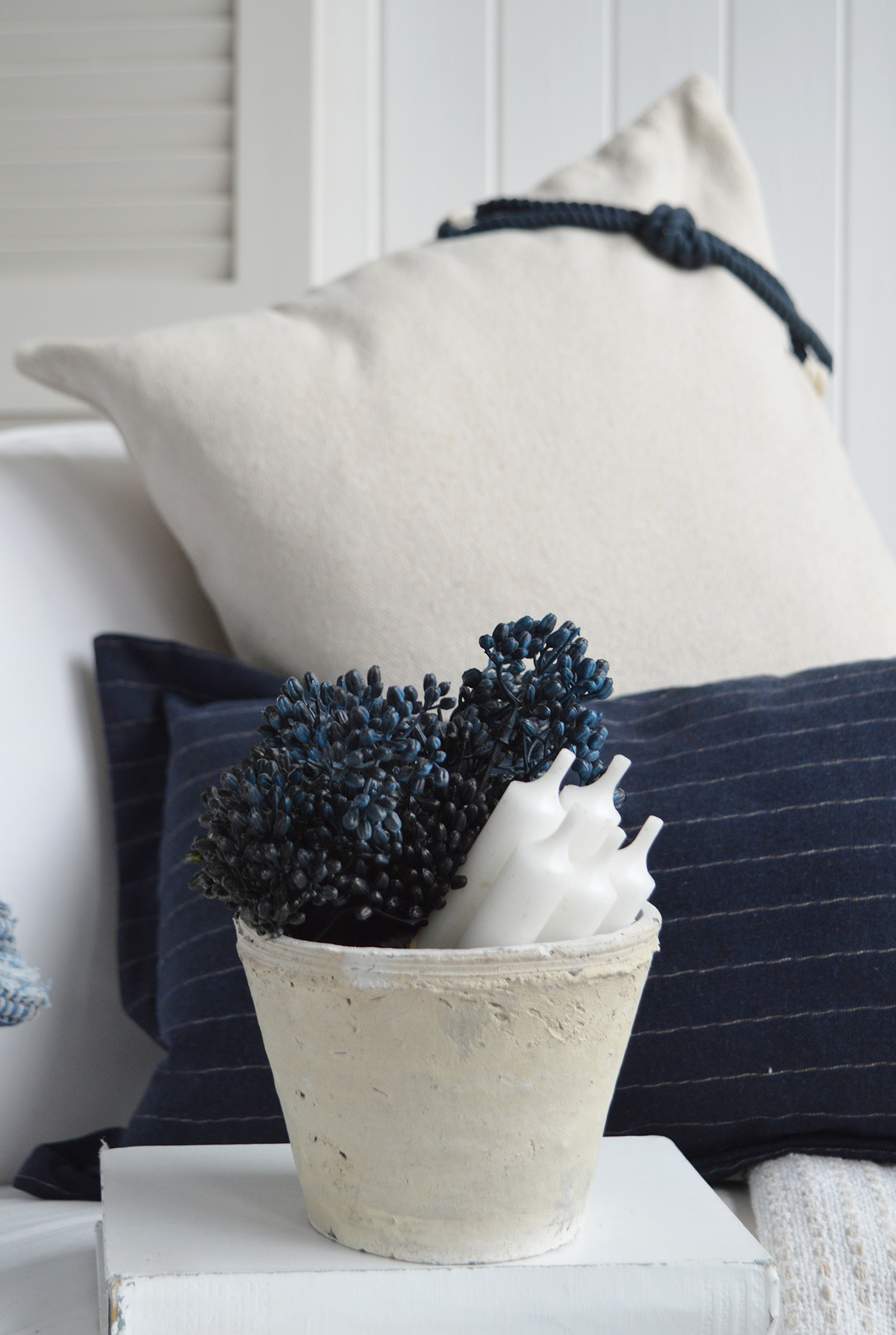 Rustic coastal pot with navy faux berries and white candles styled with Hamptons navy and cream cushions