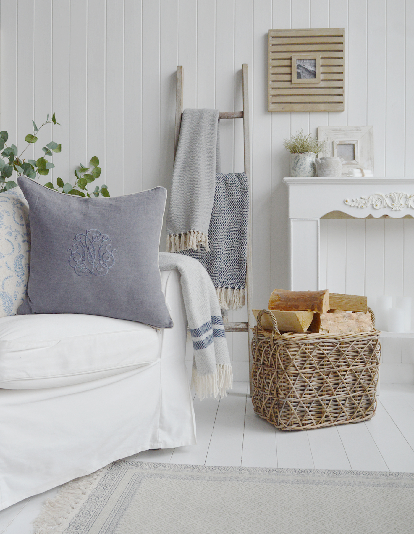 A living room in whites and neutral colours, baskets to add netural texture and soft furnishings including throws ans luxury cushions to add warmth. The wooden ladder is perfect in a modern farmhouse or country home to add blankets and some height in styling
