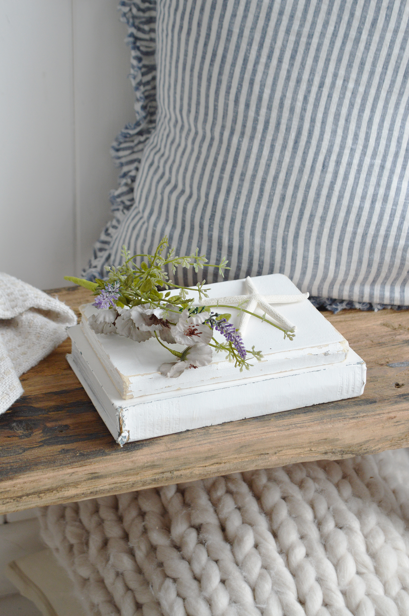 Nautical coastal decor with woven textures and sea-themed accessories showing a navy and white striped cushion