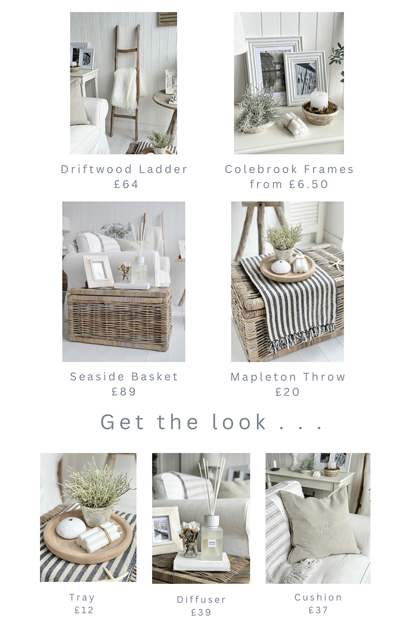 A serene New England style living room with a neutral colour palette in soft blues, greens and whites. The driftwood table with Seaside Basket tables incorporate natural materials for a rustic touch, adding warmth to the space. Throws and cushions enhance the relaxed atmosphere, along with subtle coastal elements in the decor including the striped Mapleton throws, faux coral and faux greenery