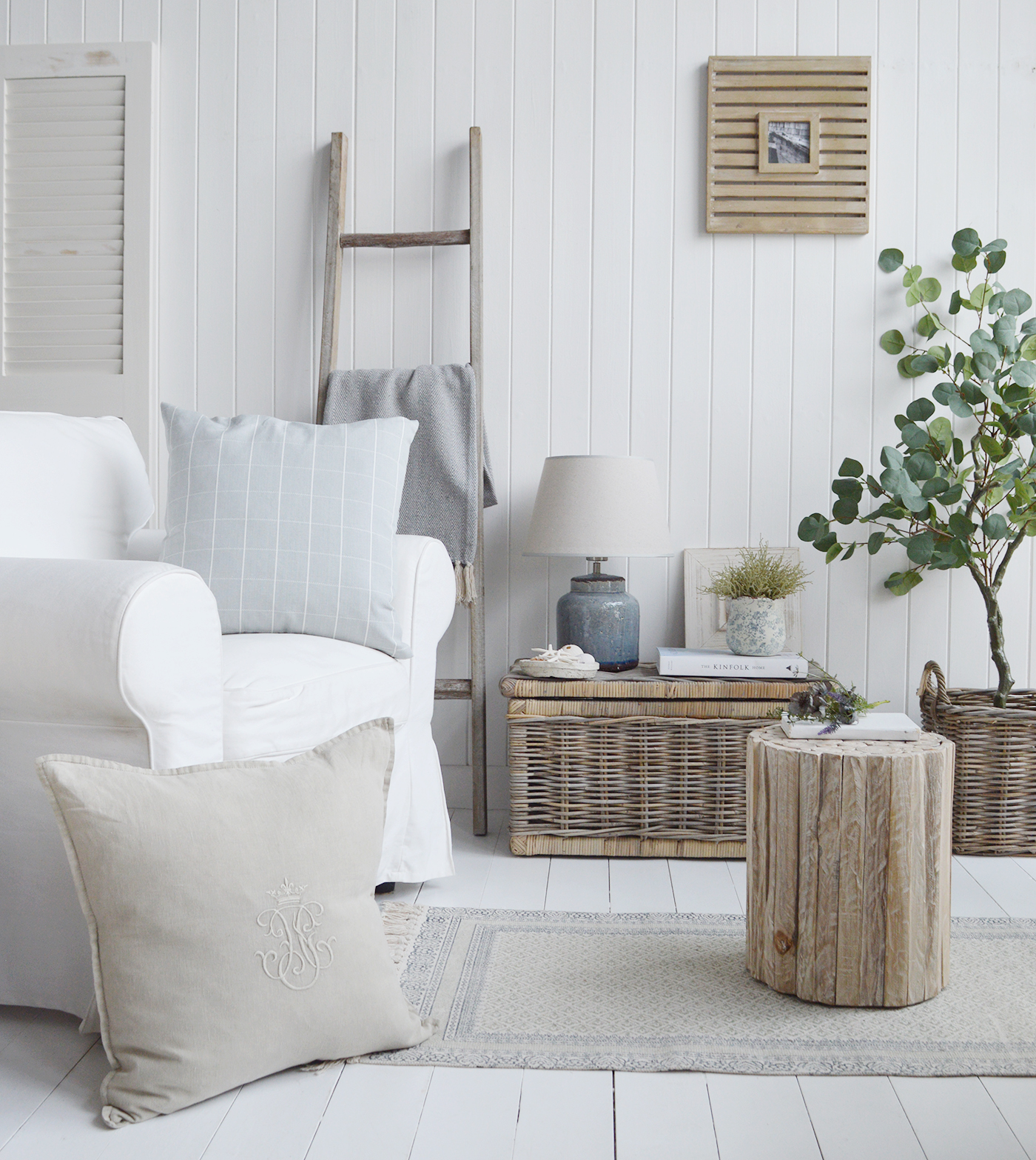 New England and Hamptons interiors in UK. Coastal furniture with luxury cushions for softness, baskets for texture, natural wood pieces of furniture for warmth and a touch of greenery alongside the Blue Compton lamp and ceramic pieces