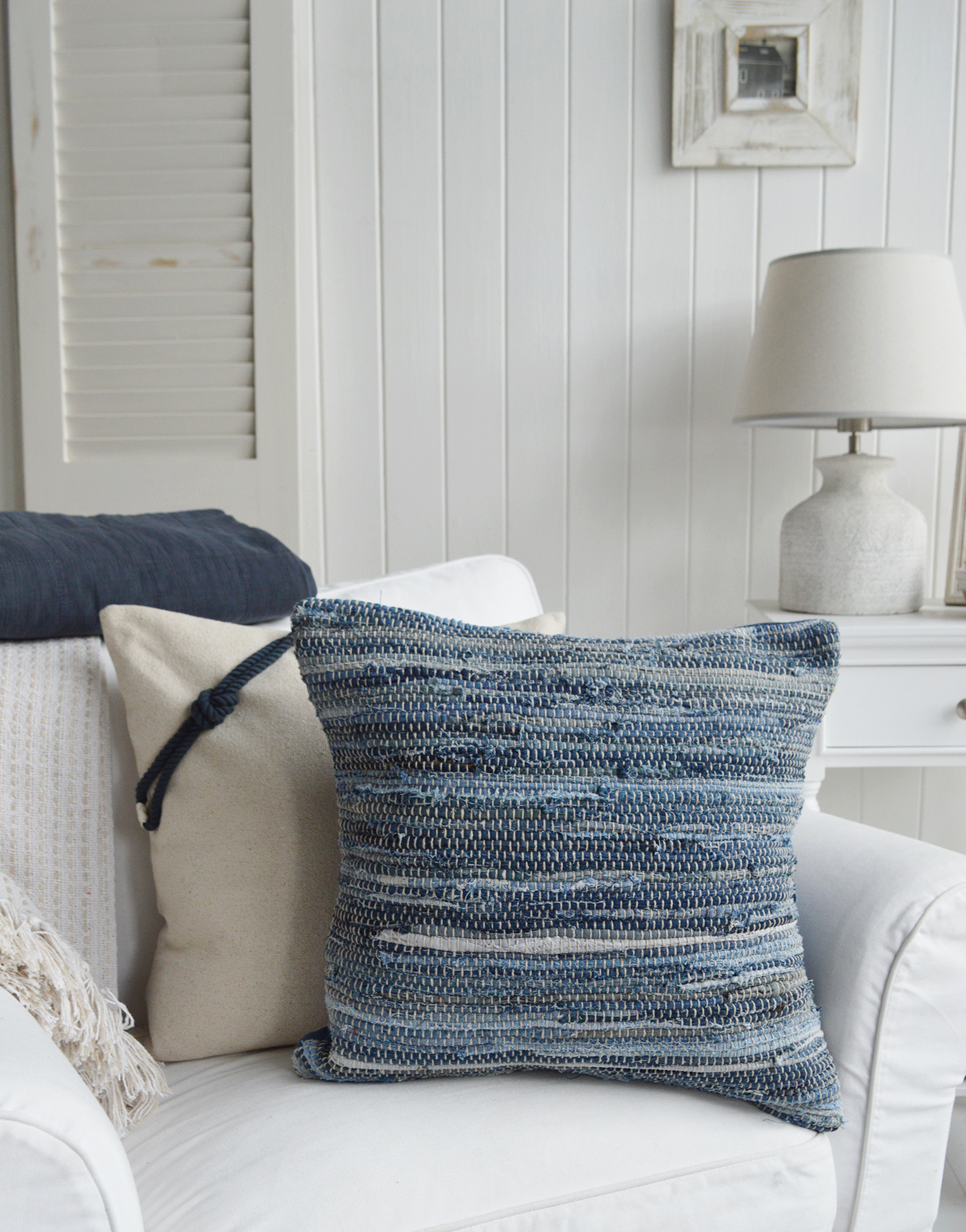 	Handwoven cushion inspired by ocean hues, ideal for beach-style interior settings