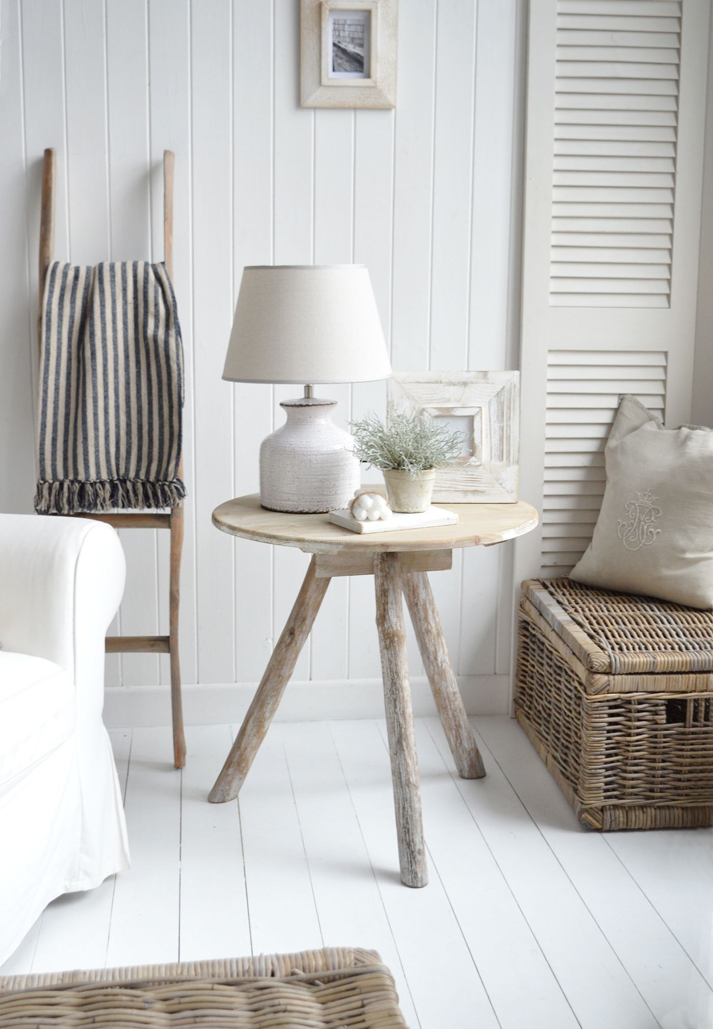 The white ceramic Compton lamp on the Driftwood table with the Mapleton throw in navy and driftwood blanket ladder in a subtly coastal new England or hamptons living room