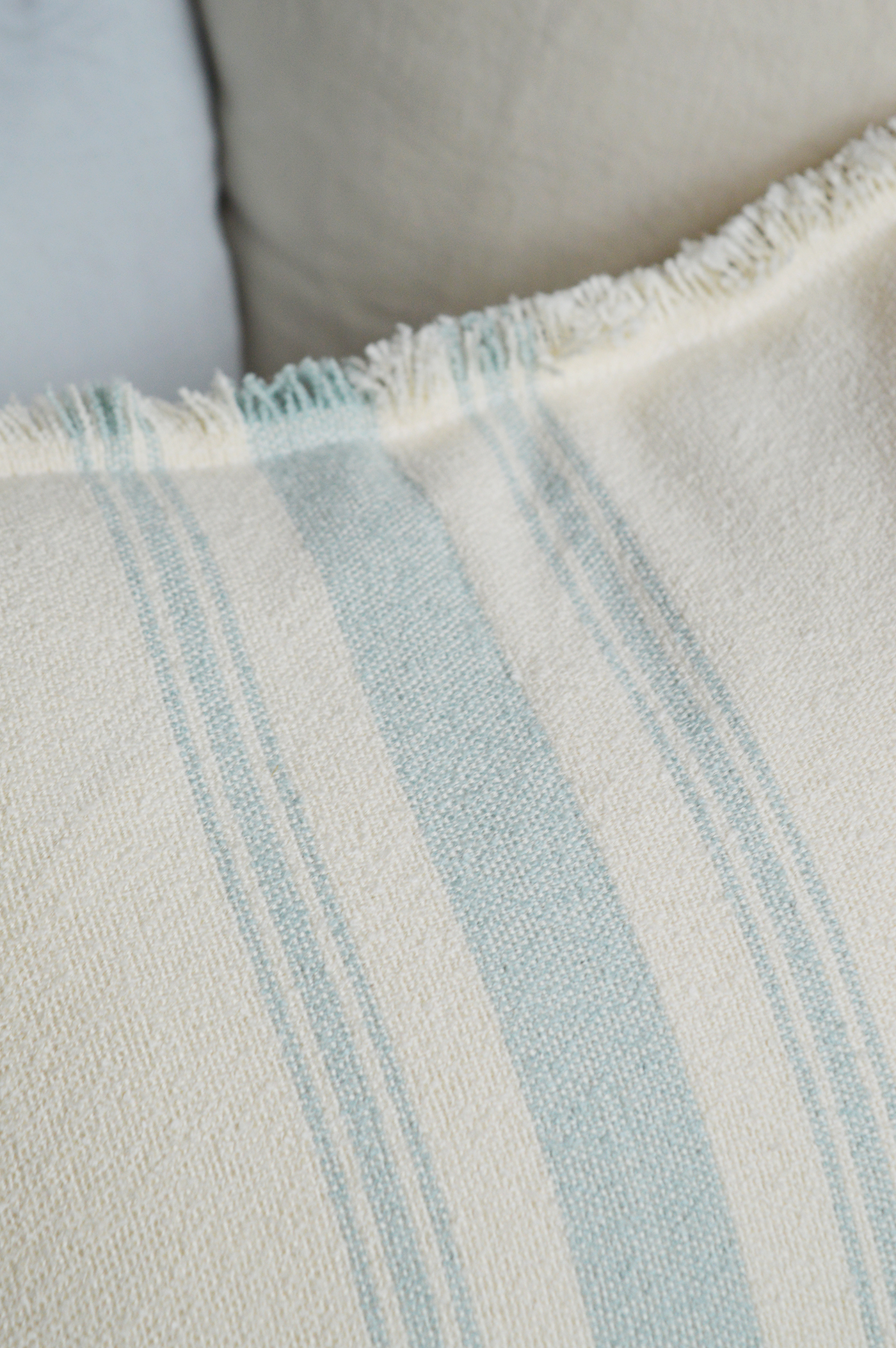 Cream cushion with blue stripes and fringe edges