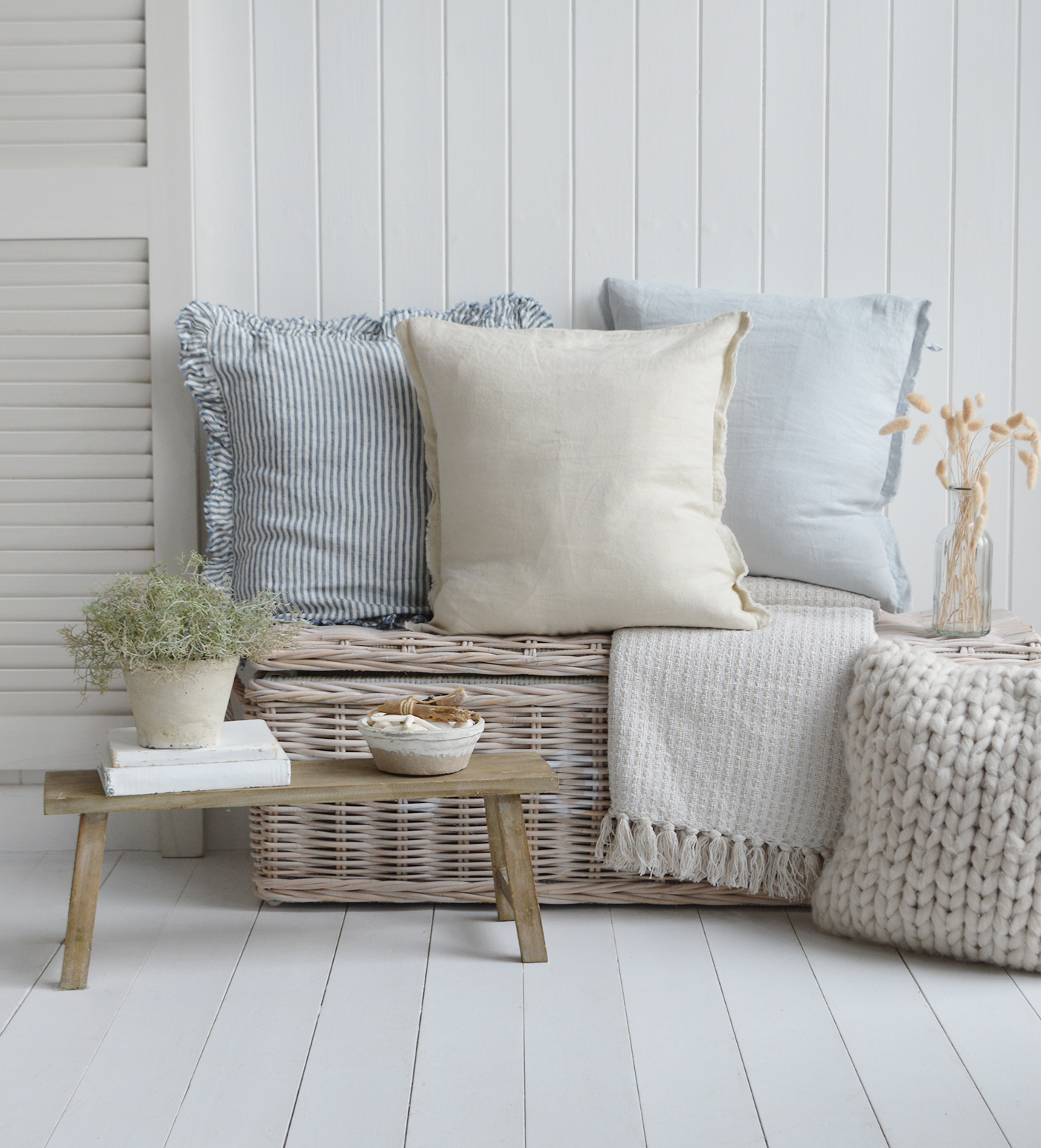 Hamptons coastal style interior with striped and linen cushions, rustic bench and potted plant”