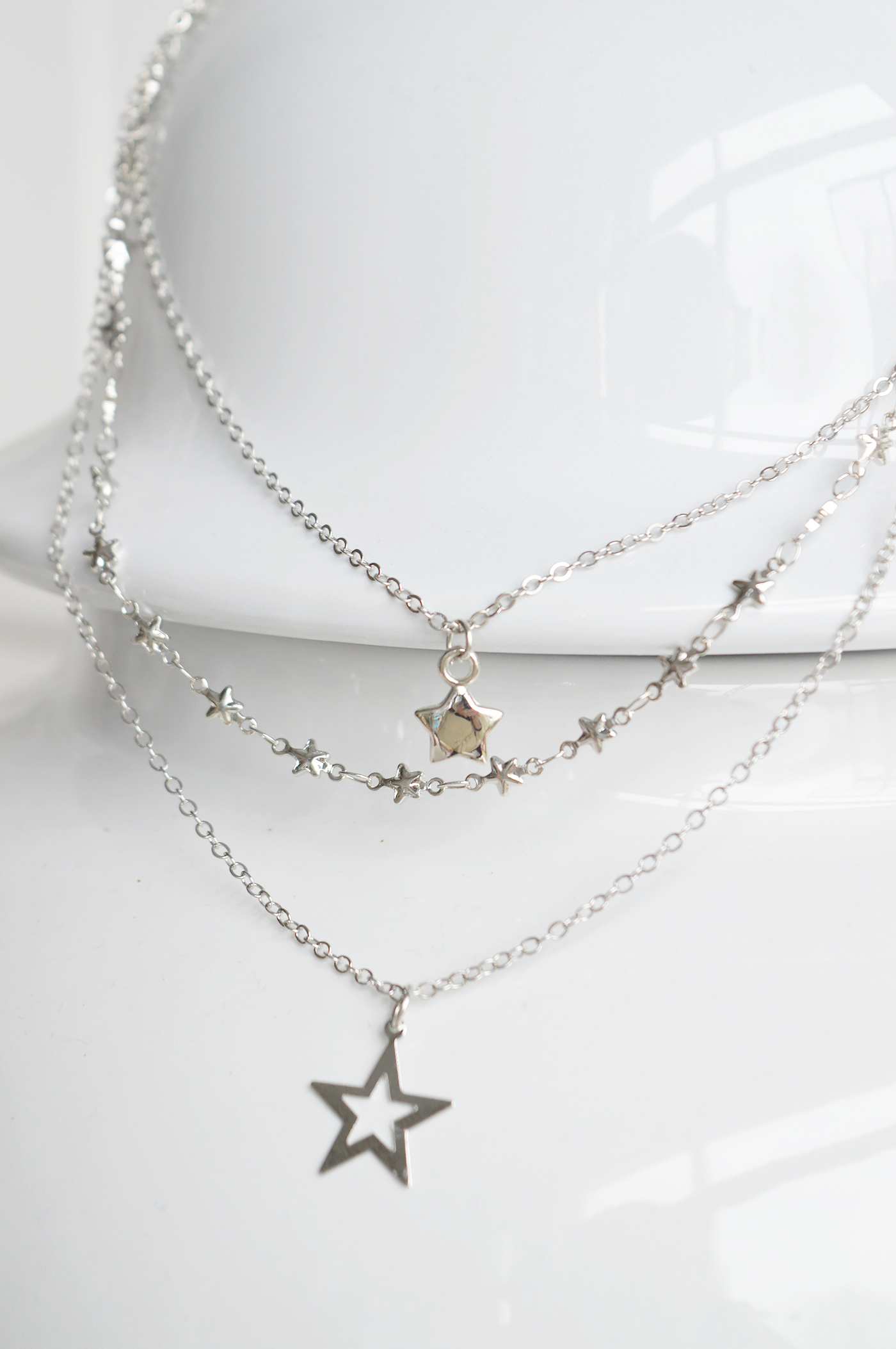 Three delicate chains create a soft layered necklace look with subtle star details.