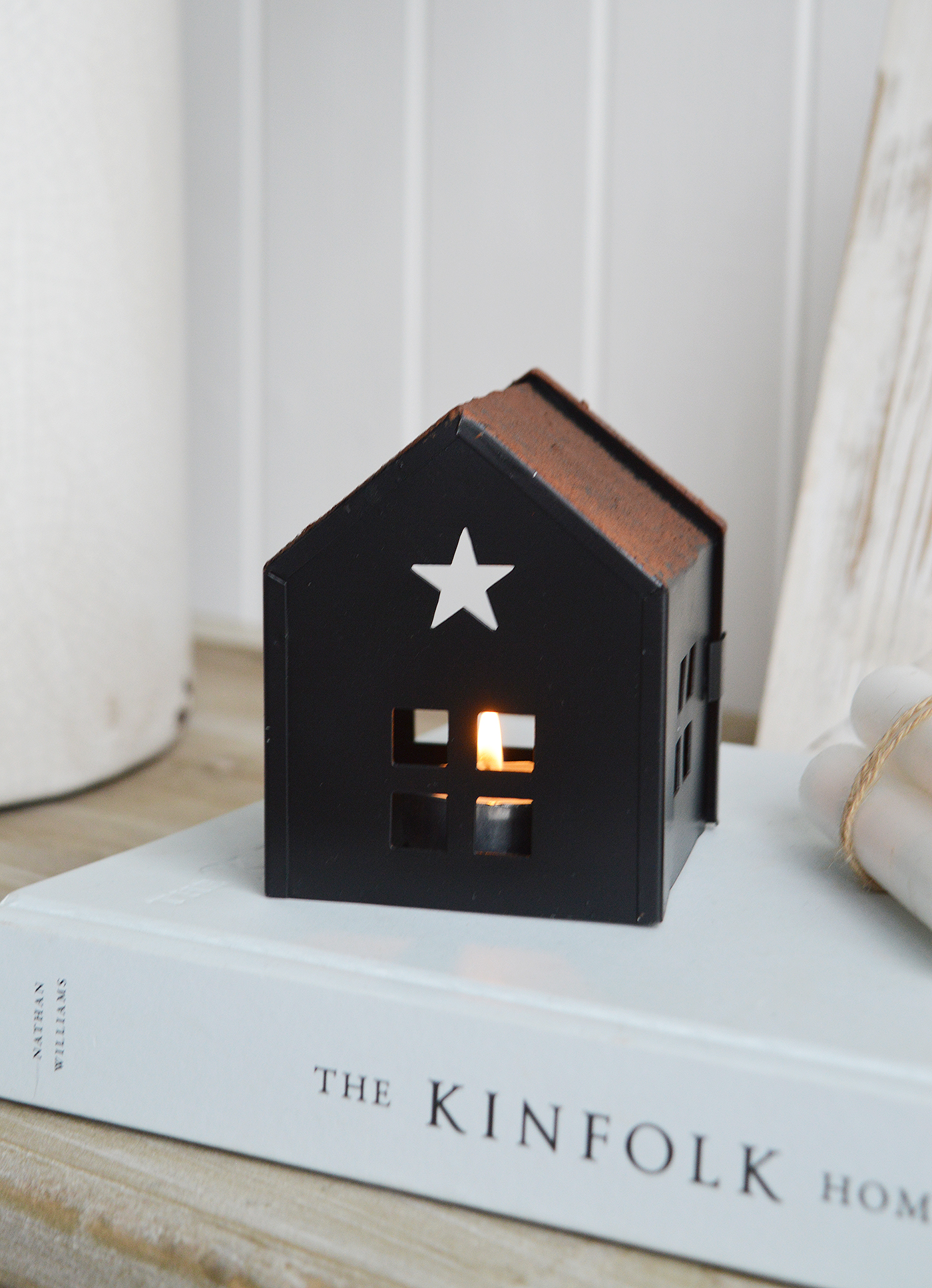 This black metal tea light holder is designed like a miniature house, with a cut-out star on the roof that lets light shine through beautifully for new England coastal and farmhouse interiors