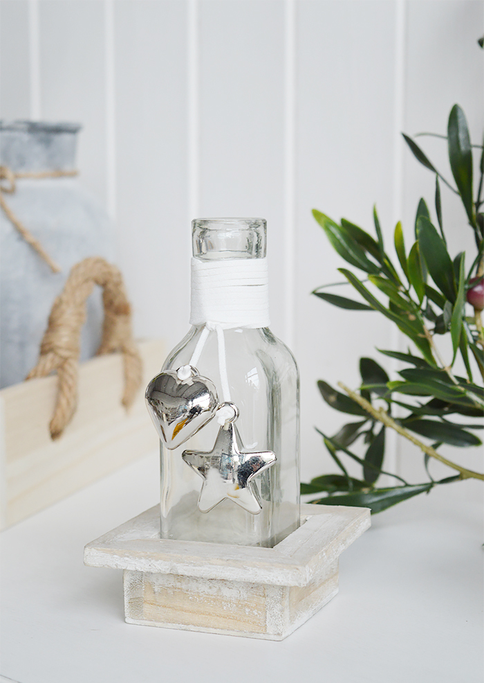 A decorative square bottle with a hanging silver mirrored chunky heart and star in a driftwood style wooden crate