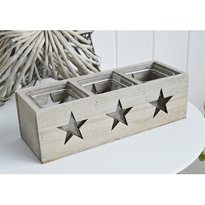 The Nantucket wooden triple candle holder with glass cups for a candles and cut out stars on the back and front with to the light to light up the stars.