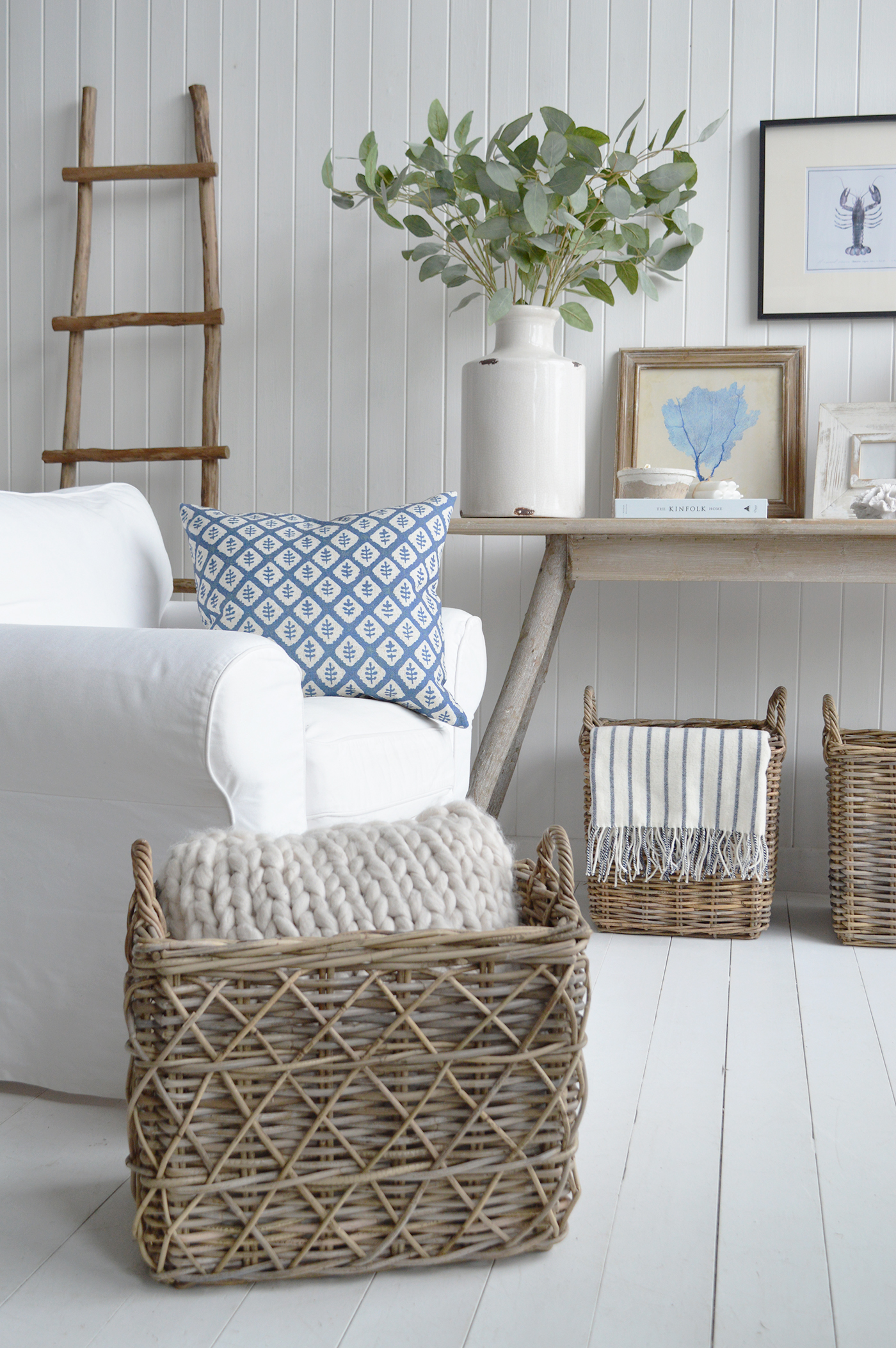 Natural materials like woven baskets and weathered driftwood accents, touched with soft hints of blue, bring effortless elegance to a Hamptons coastal-inspired interior.