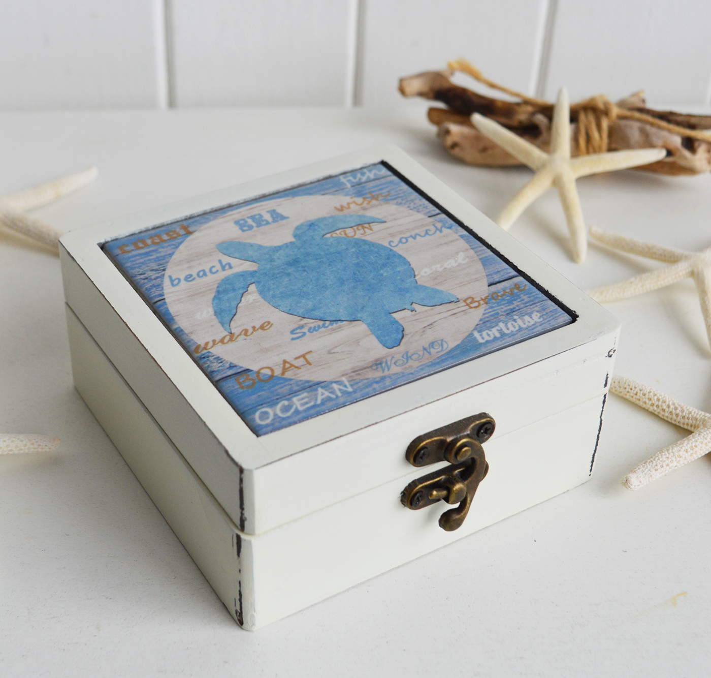 This coastal coaster set includes four ceramic coasters with unique ocean-inspired designs, neatly stored in a charming wooden box.