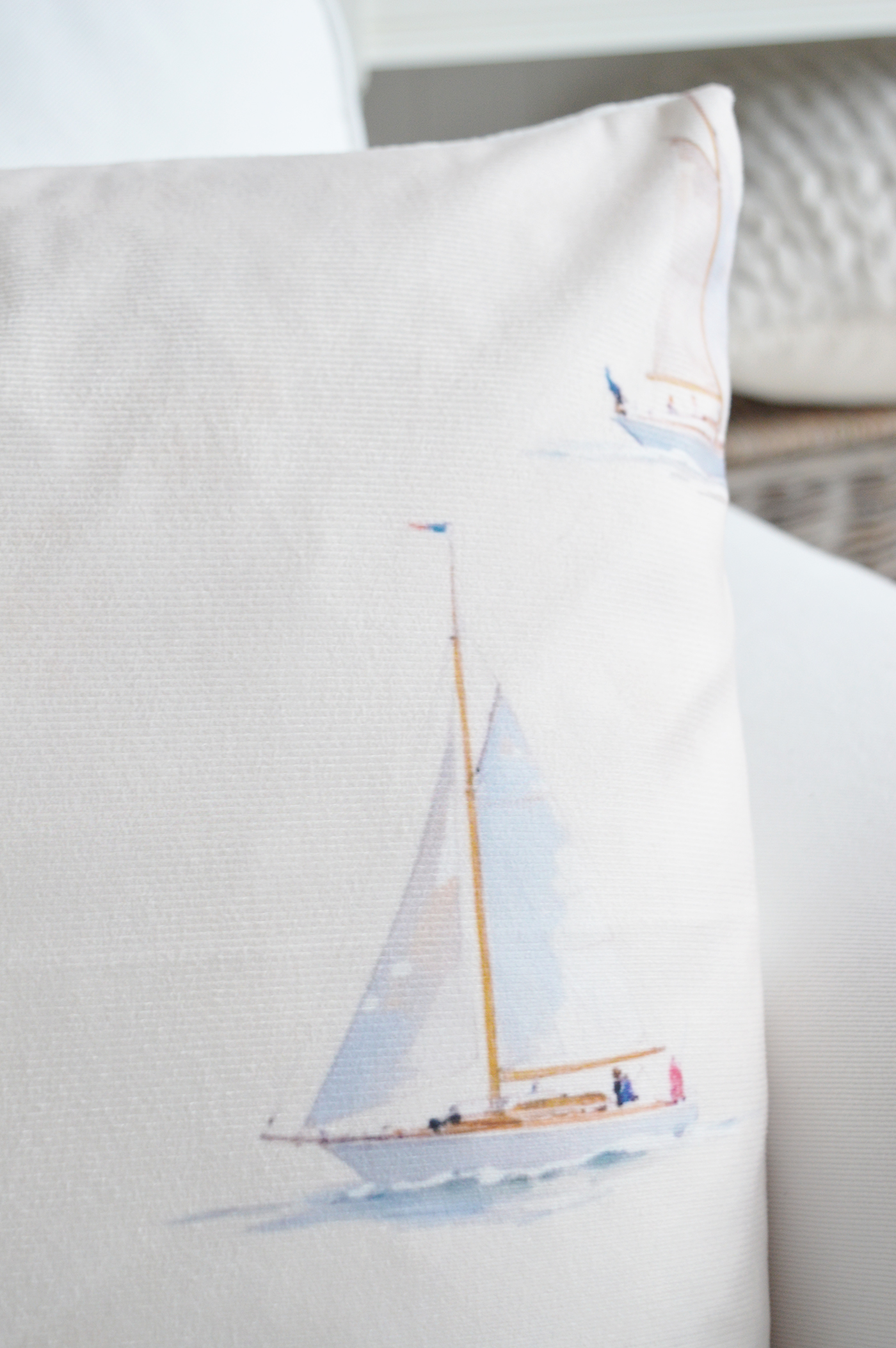 Sailboat patterned cushion layered with blue and neutral cushions.