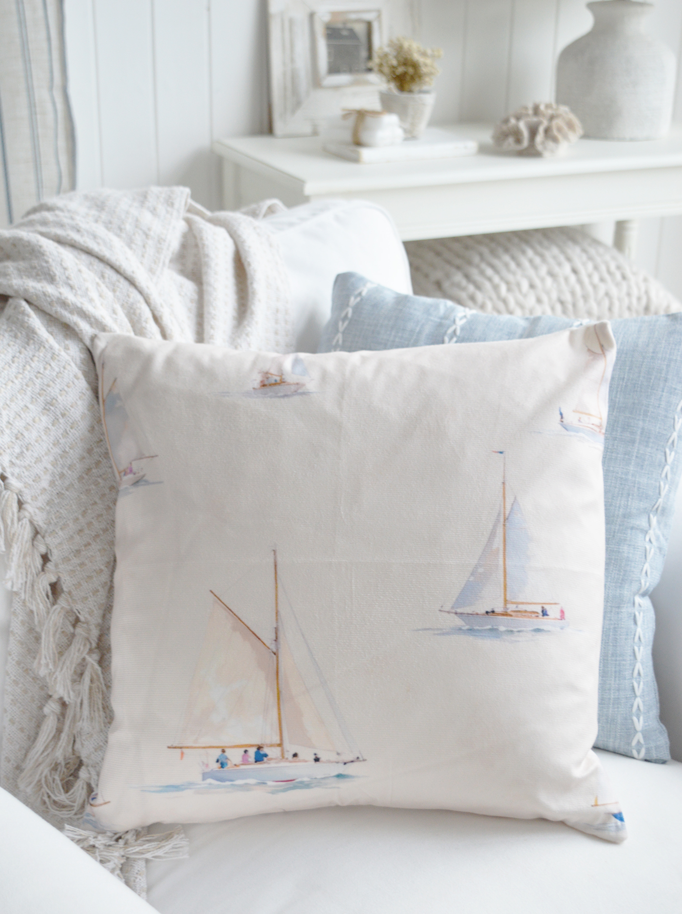 Watercolour sailboat cushion cover styled in a coastal living room.