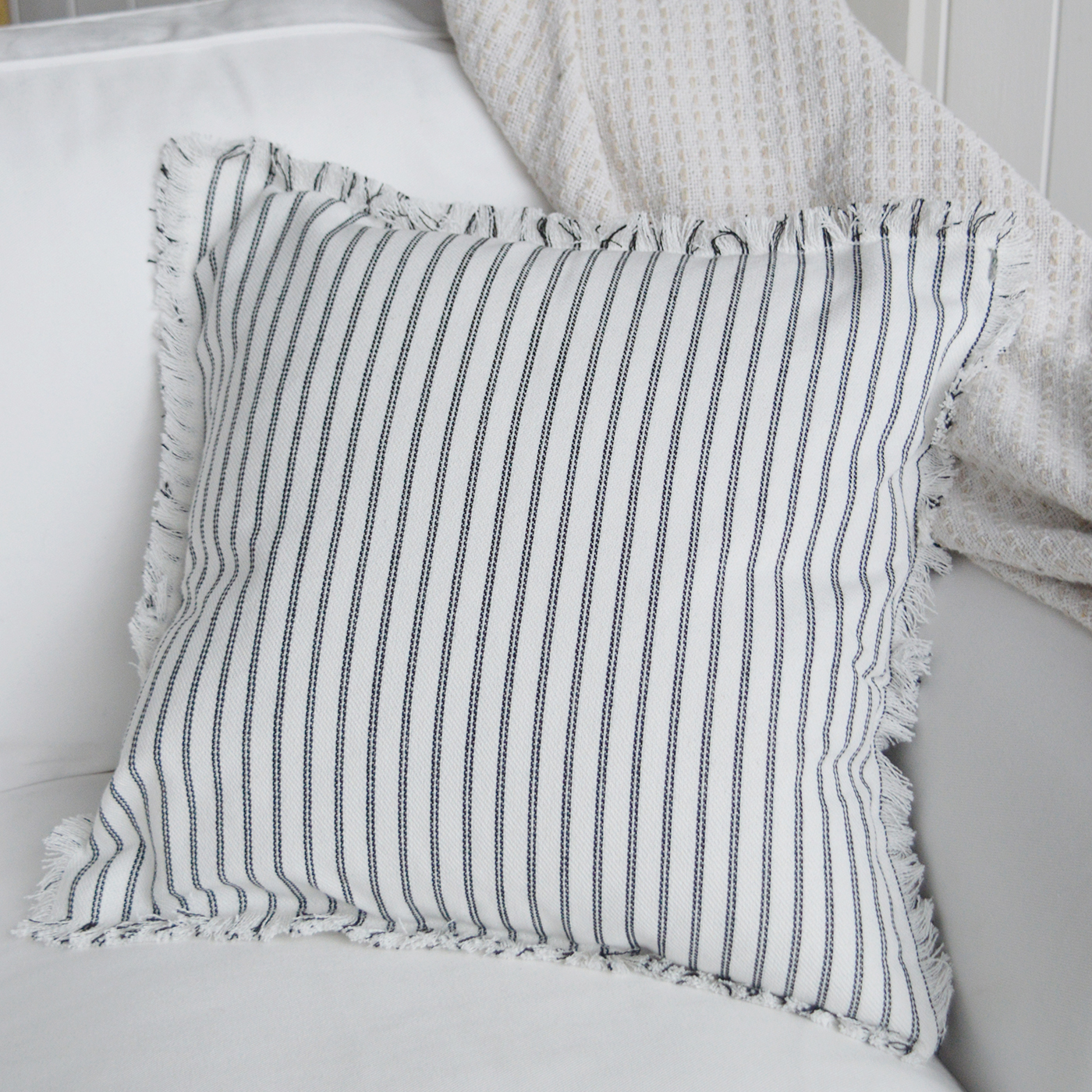 Coastal-inspired striped cushion cover adding texture to a white sofa.