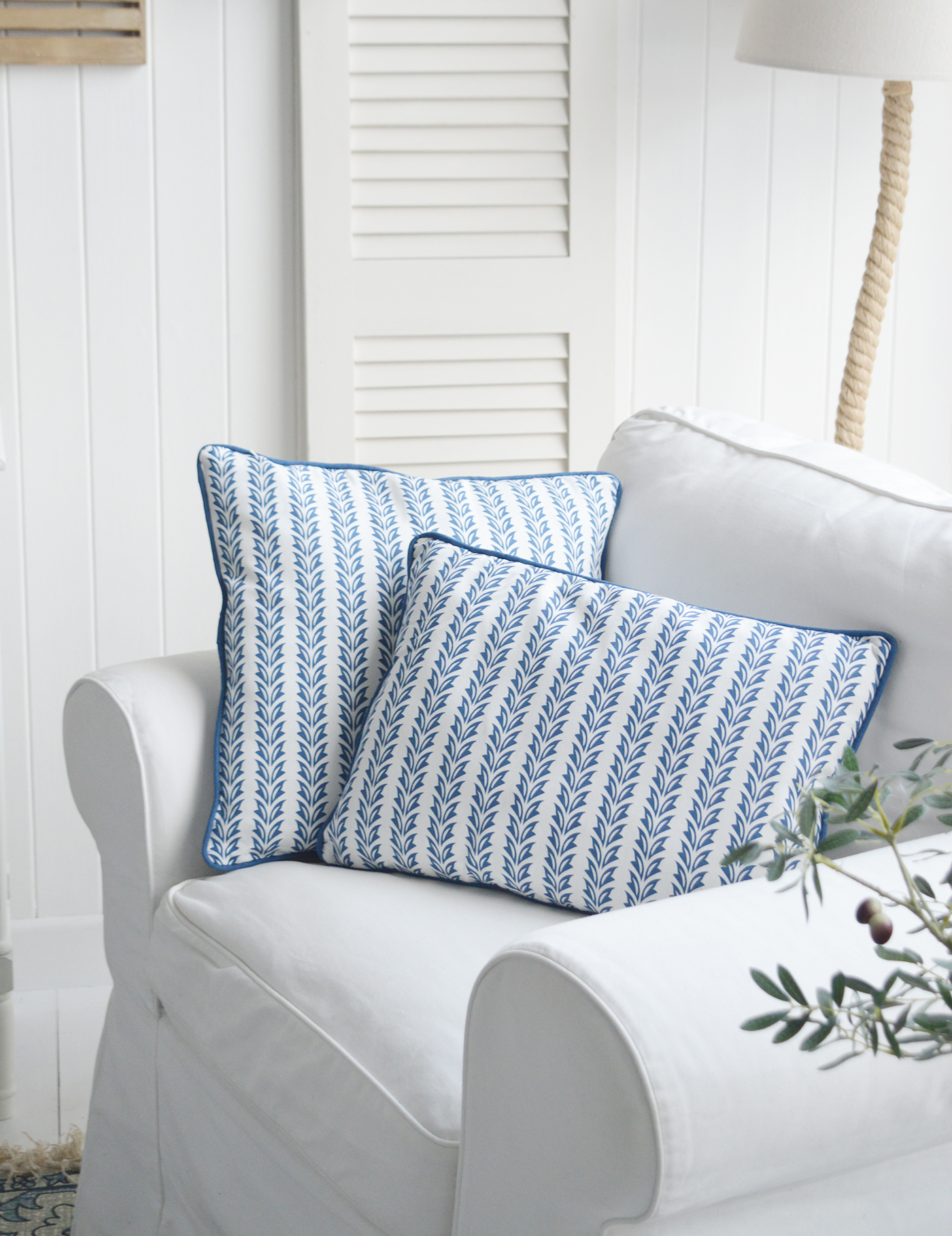 The blue and white cushions echo the crisp tones of the Atlantic, adding a breezy charm to the sun-drenched living room.