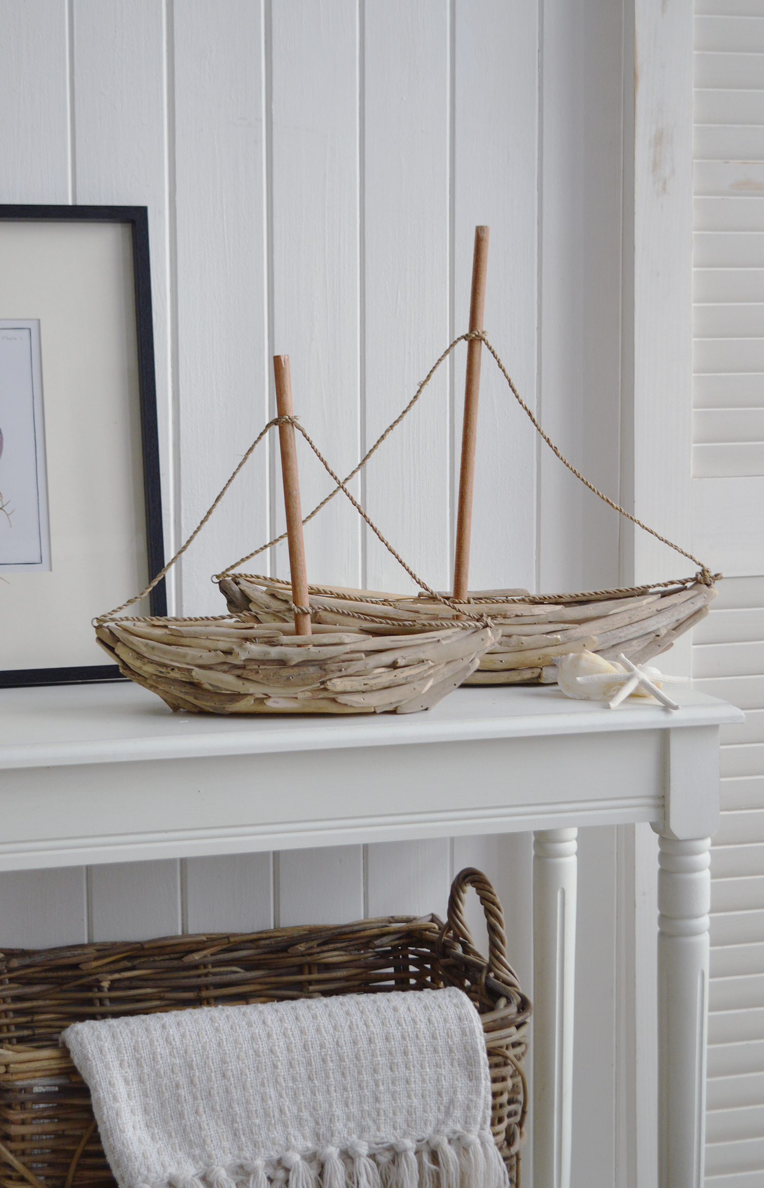 Pair of handcrafted driftwood yachts with rope rigging styled on white coastal console table
