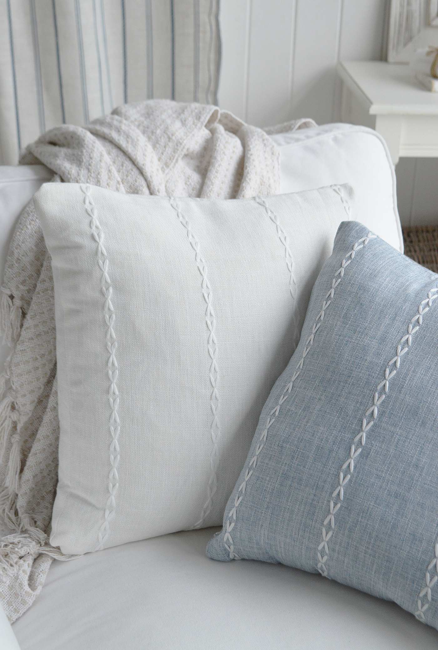 Soft white cushion cover with subtle embroidery on a white sofa.