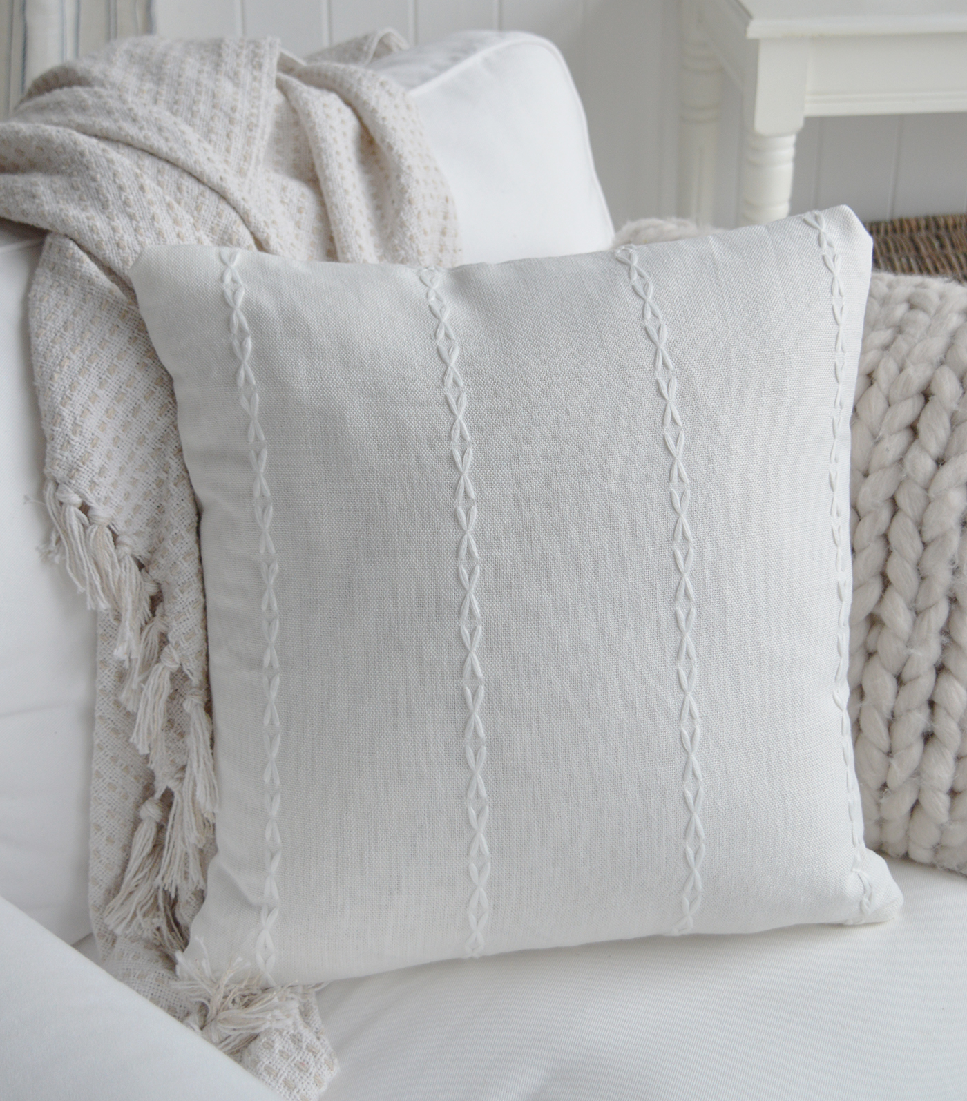 White textured cushion with delicate stitched detailing styled in a coastal living room.