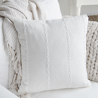 White Friendship cotton cushion with stitched stripes styled alongside a blue coastal cushion.