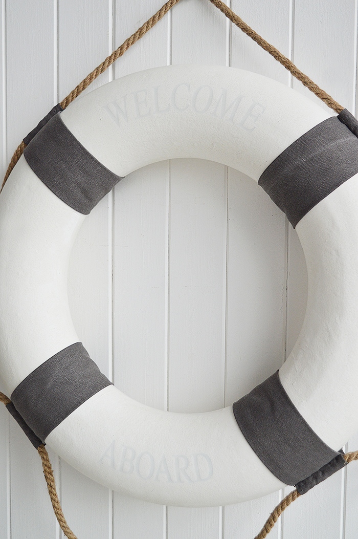 A white and grey vintage style lifebuoy.

The complementing grey and white along with the natural rope and subtle Welcome Aboard offer a touch of Coastal Chic decor to your room