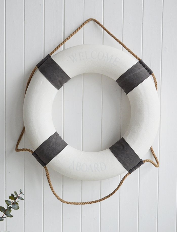 A white and grey vintage style lifebuoy.

The complementing grey and white along with the natural rope and subtle Welcome Aboard offer a touch of Coastal Chic decor to your room