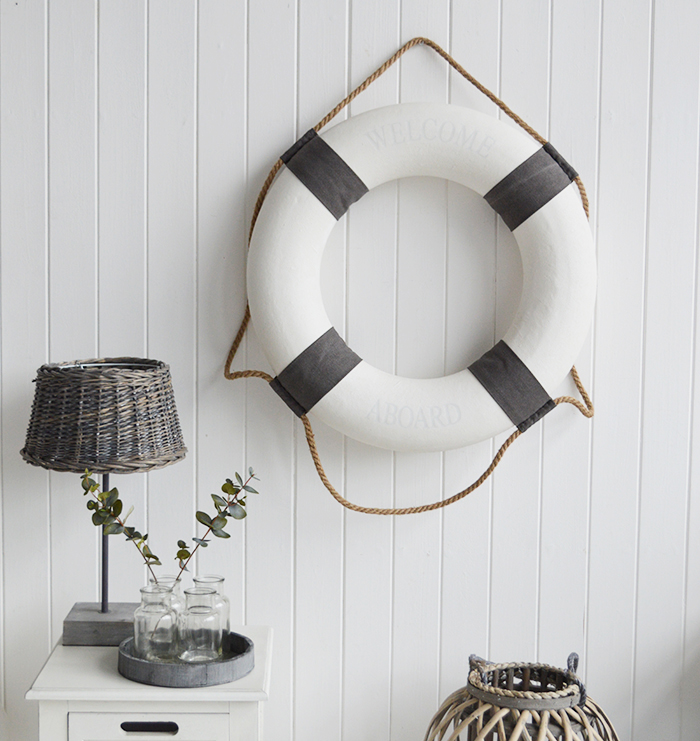 A white and grey vintage style lifebuoy.

The complementing grey and white along with the natural rope and subtle Welcome Aboard offer a touch of Coastal Chic decor to your room