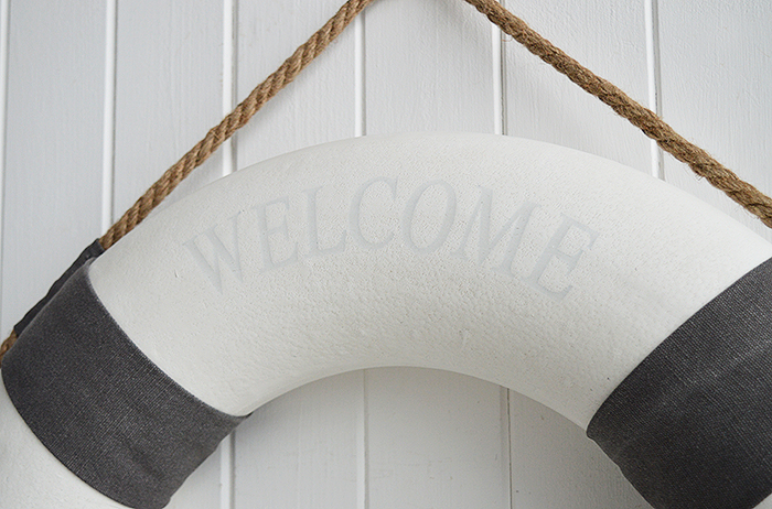 A white and grey vintage style lifebuoy.

The complementing grey and white along with the natural rope and subtle Welcome Aboard offer a touch of Coastal Chic decor to your room