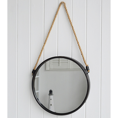 A circular porthole style mirror on a rope with aged dark grey metal surround.    Gorgeous in a coastal bathroom or hanging above a dressing or console table