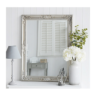 A large silver wall mirror with decorative carved Fleur De Lis detailed chunky silver frame for a chic style to any bedroom, living room, hall or bathroom. The mirror can be wall hung or simply rest on a table top for dressing or console table.