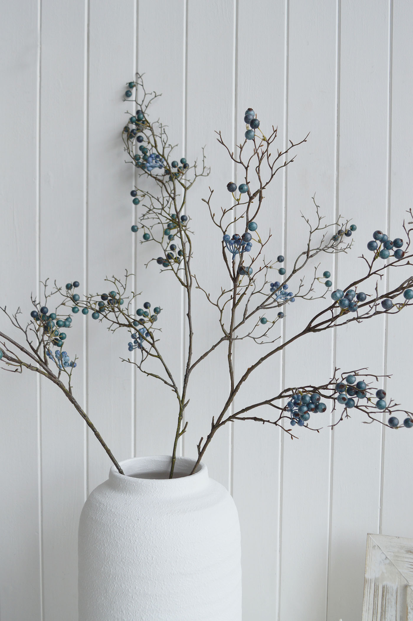 Soft blue faux blueberry branches bring a calm coastal touch to whitewashed interiors, perfect for styling console tables, shelves and beach house living spaces.