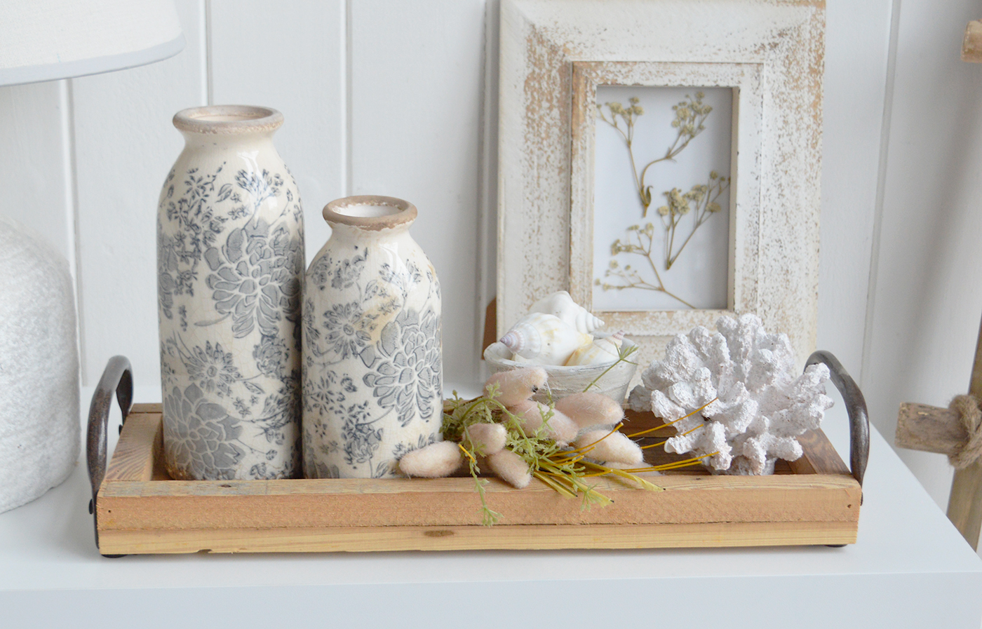 Create an inviting coastal console table display with muted florals, soft meadow textures and rustic wood.