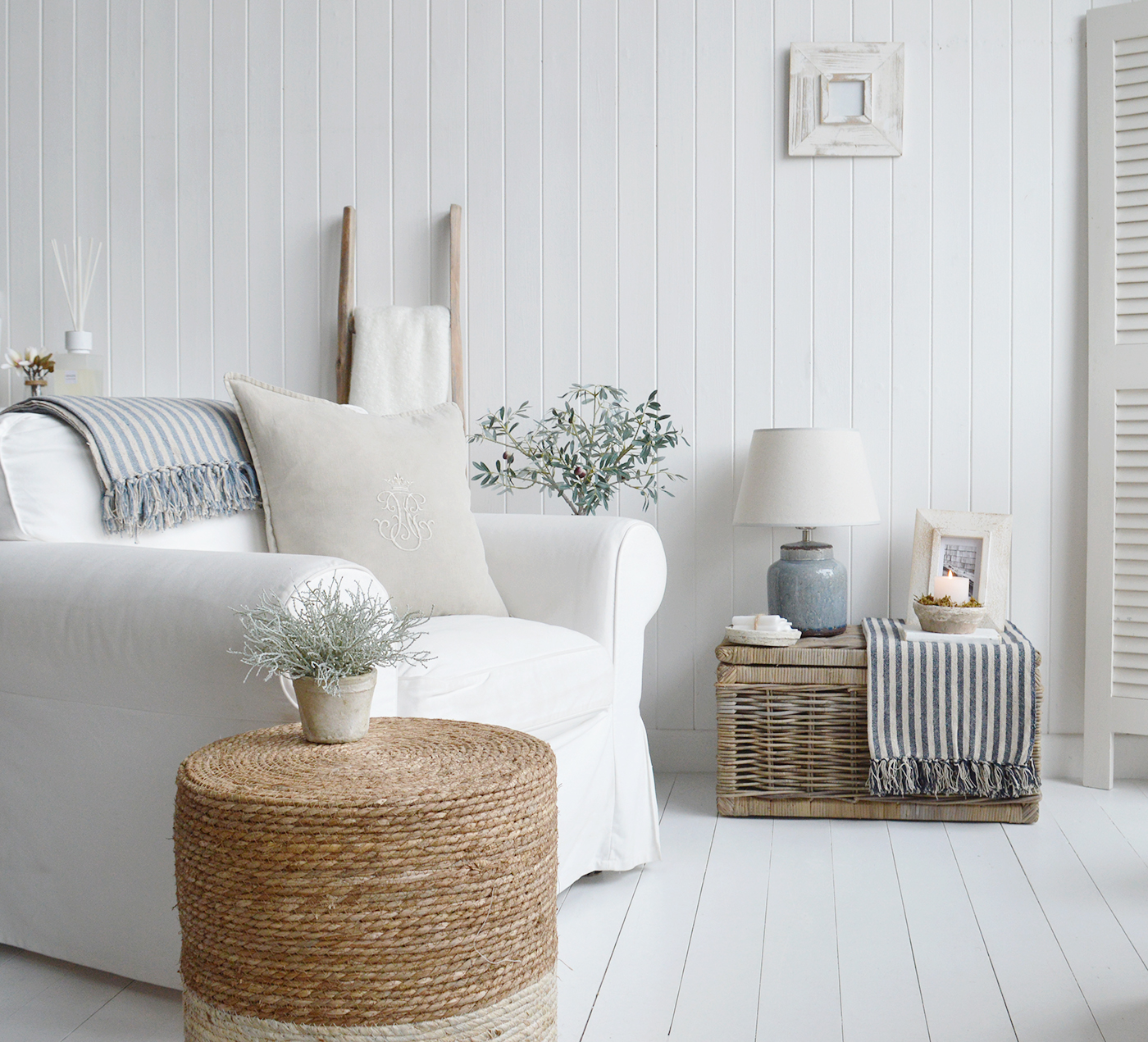 A white and blue living room for a luxurious Hamptons modern farmhouse feel - showing our pieces of modern farmhouse and country furniture including the Seaside basket table, Fall river stool, Driftwood ladder and beach house cushions and throws