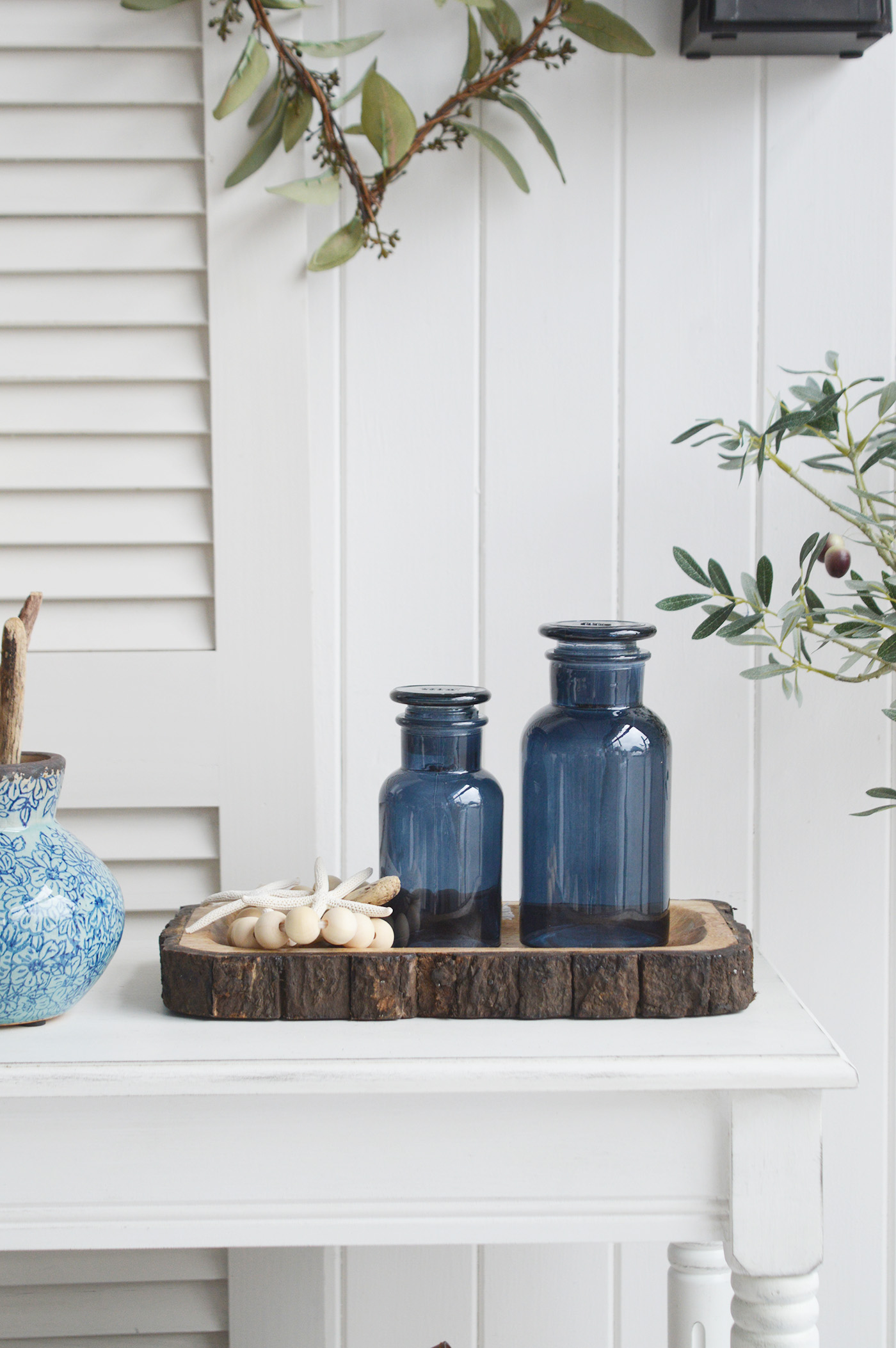 Decorative Blue glass bottles on the tree trunk rustic tray for New England style living in coastal and country homes and furniture
