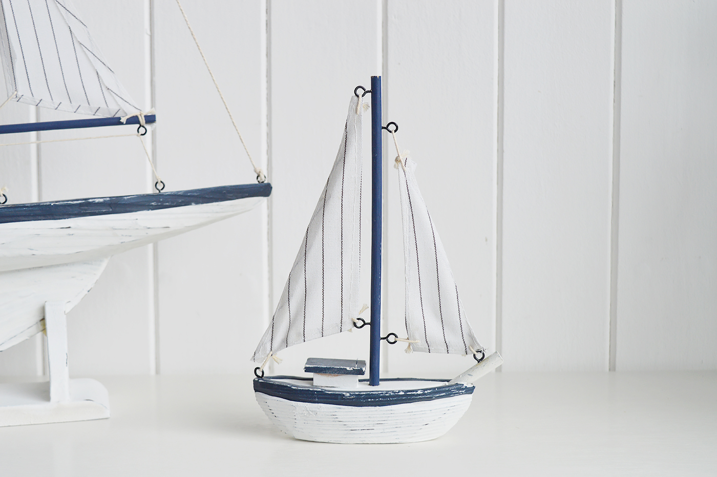 White Furniture and accessories for the home. A decorative white and blue yacht. Coastal Nautical Interior design Accessories for New England style homes and interiors