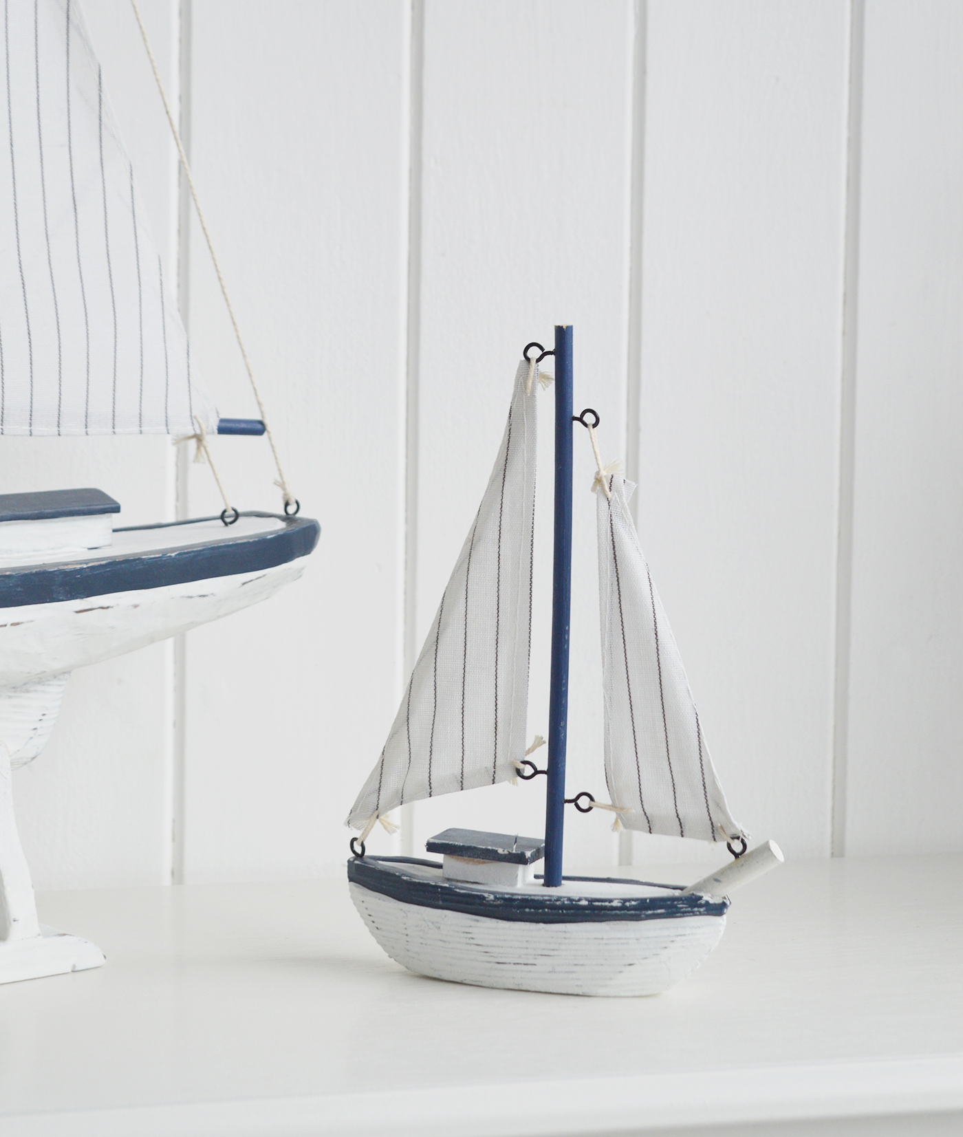 White Furniture and accessories for the home. A decorative white and blue yacht. Coastal Nautical Interior design Accessories for New England style homes and interiors