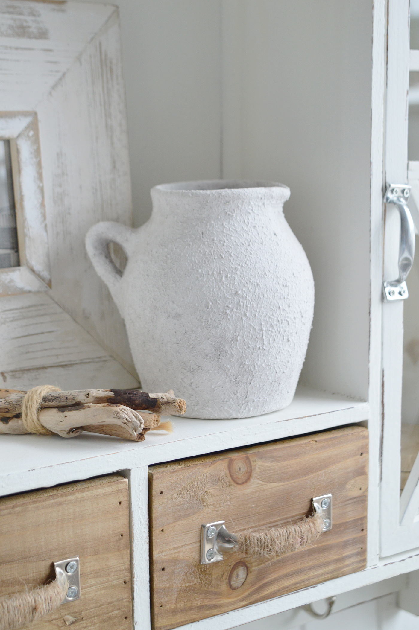 Modern country interiors with rustic drawers, ceramic jug, driftwood, and coastal chic Hamptons details