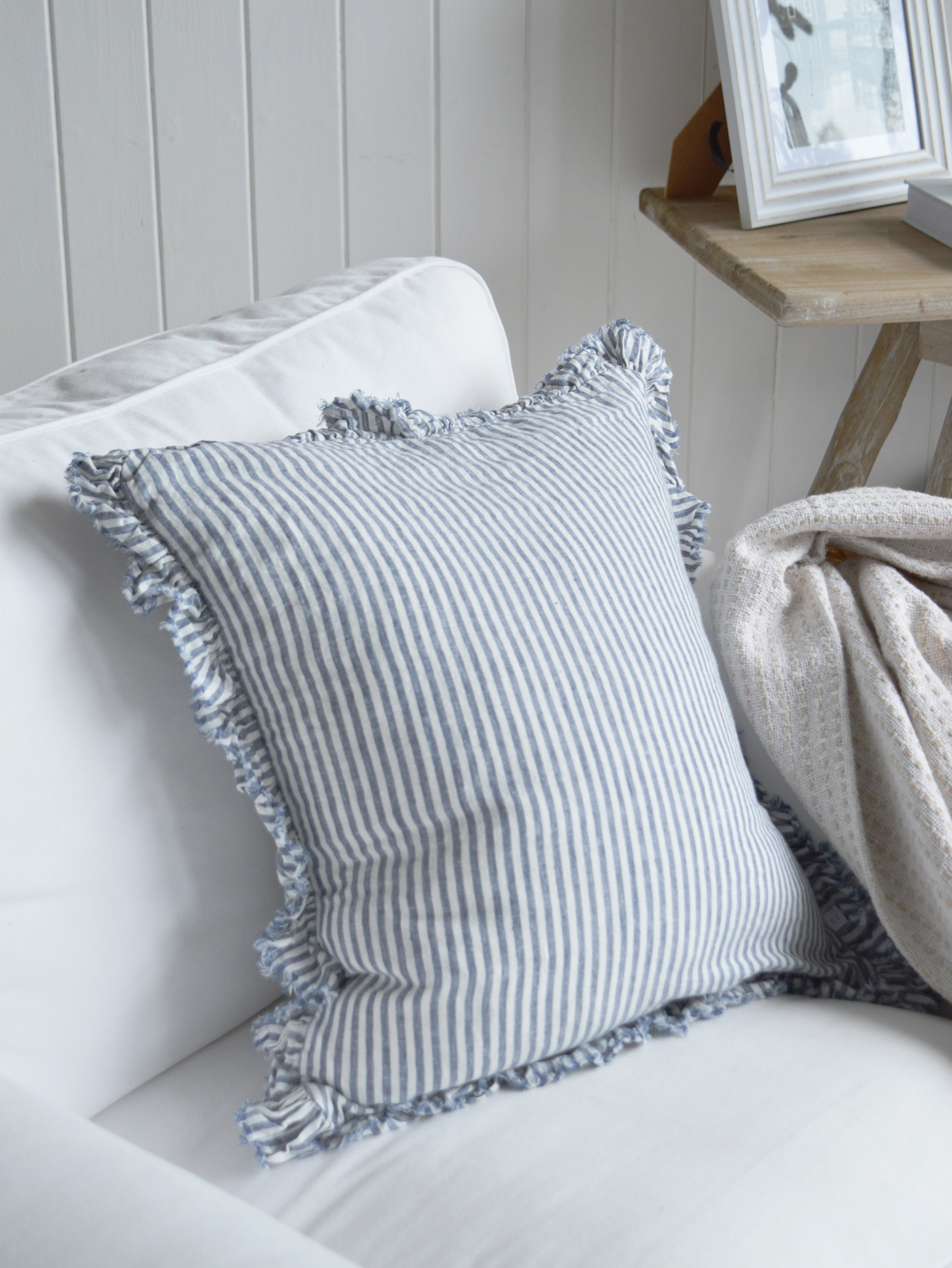 Modern country interiors with striped cushion, neutral throw, and coastal chic Hamptons accents.