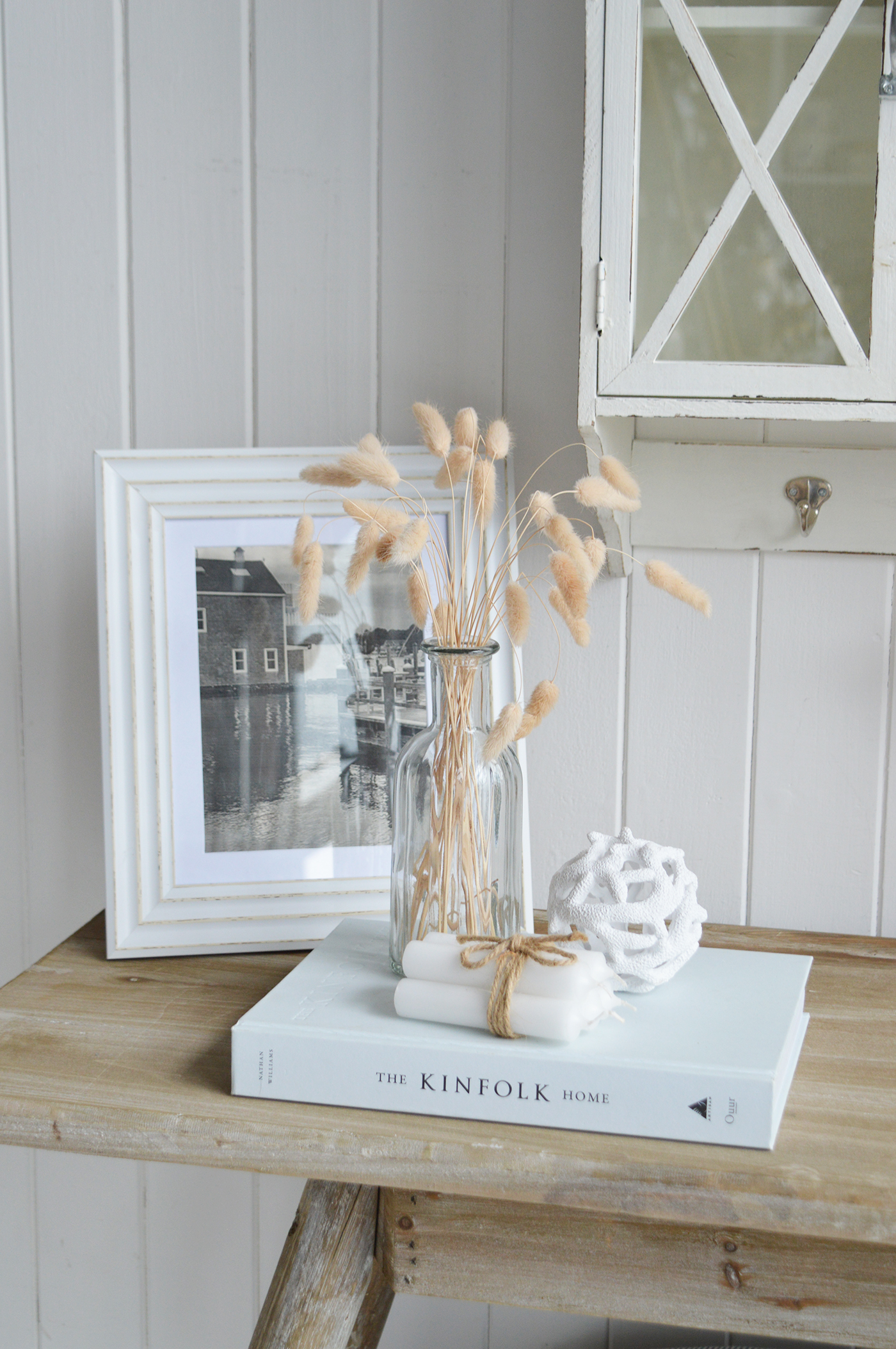Modern country interiors with glass vase, dried grasses, framed artwork, and coastal chic Hamptons accents