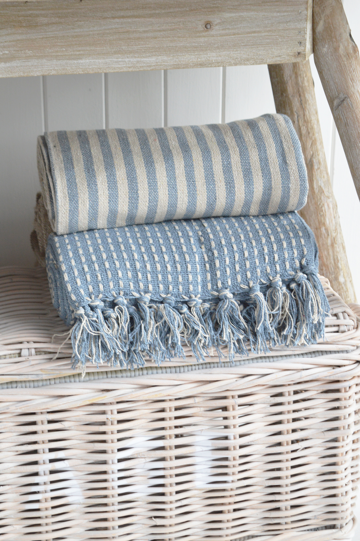 Modern country interiors with folded woven throws on wicker trunk in coastal chic Hamptons style