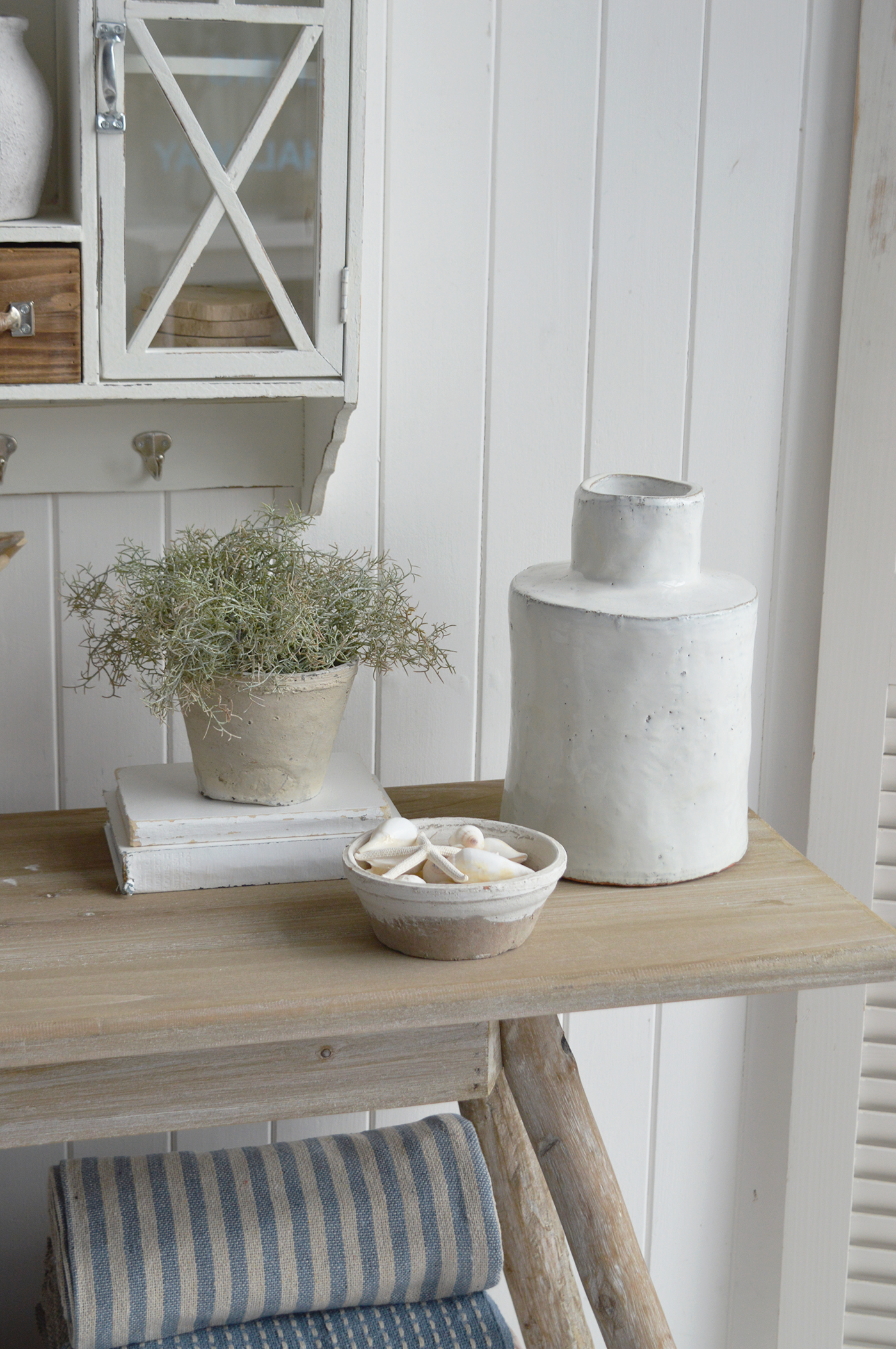 Modern country interiors with rustic console, ceramic jug, potted plant, and coastal chic Hamptons accents