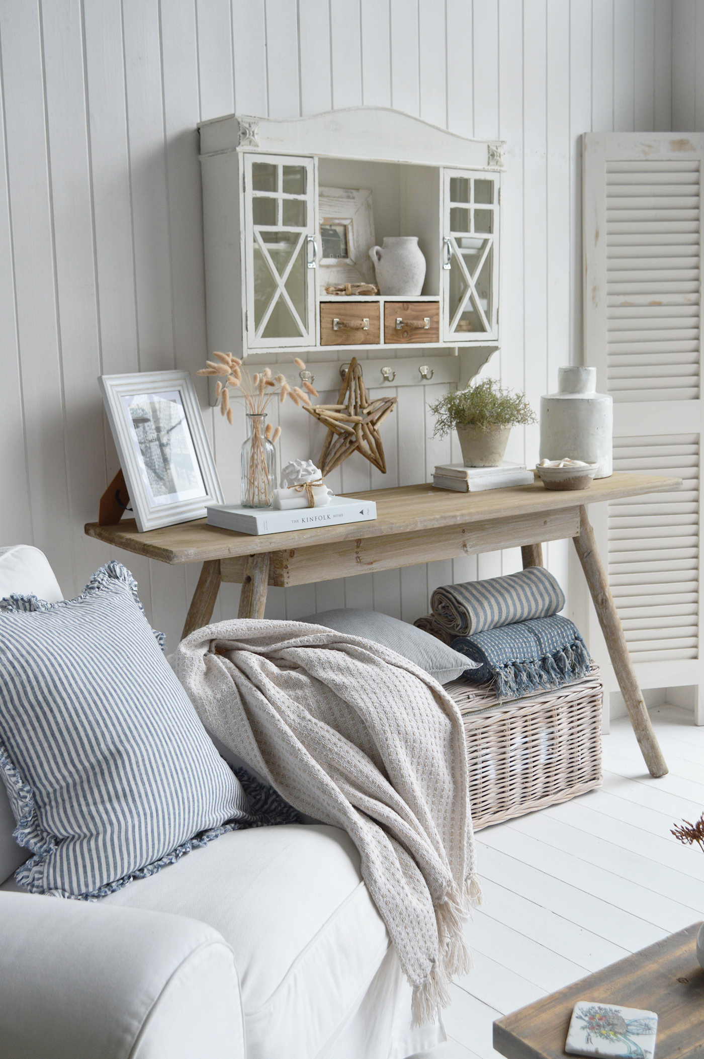 Modern country interiors with Hamptons style console, wicker basket, striped throws, and coastal chic accents.