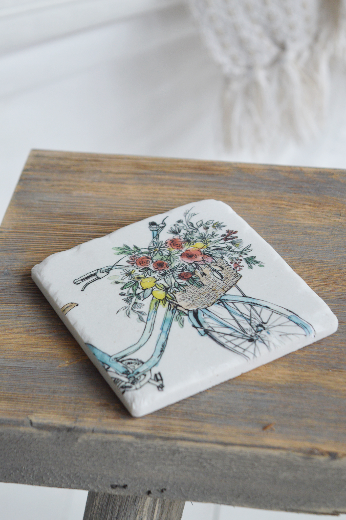 Modern country interiors with rustic stool and floral bicycle coaster in coastal chic Hamptons style.