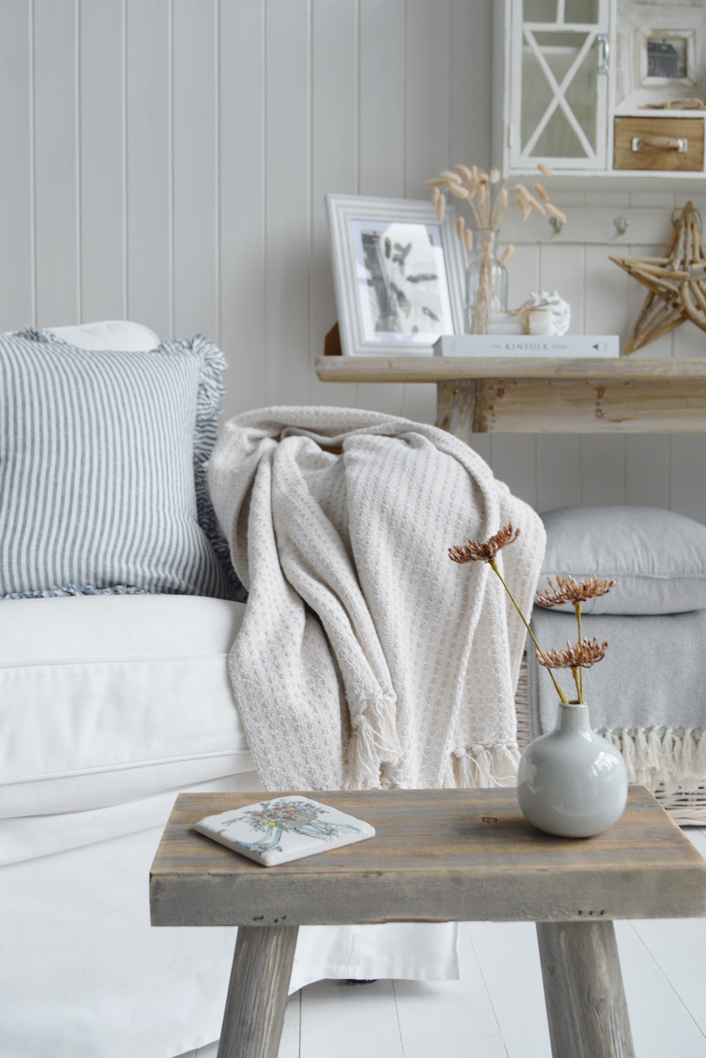 Modern country interiors with striped cushion, soft throw, rustic stool, and coastal chic Hamptons accents