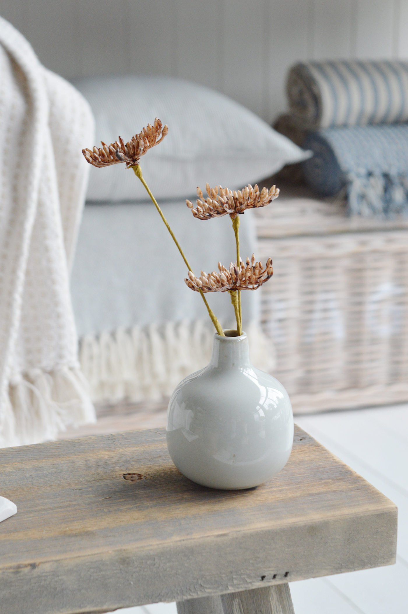 Modern country interiors with ceramic vase, rustic stool, and coastal chic Hamptons style accents