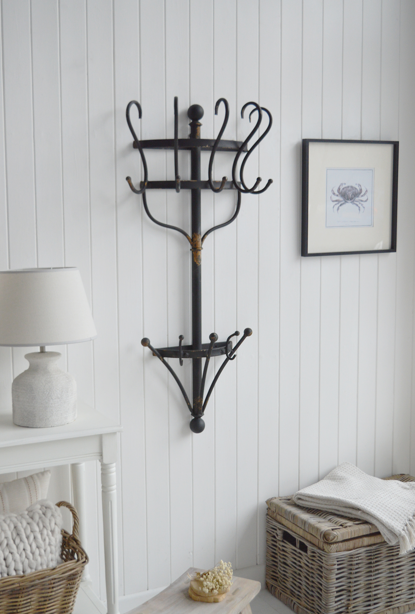 This decorative metal coat rack creates a striking feature against white walls and tongue-and-groove panelling.