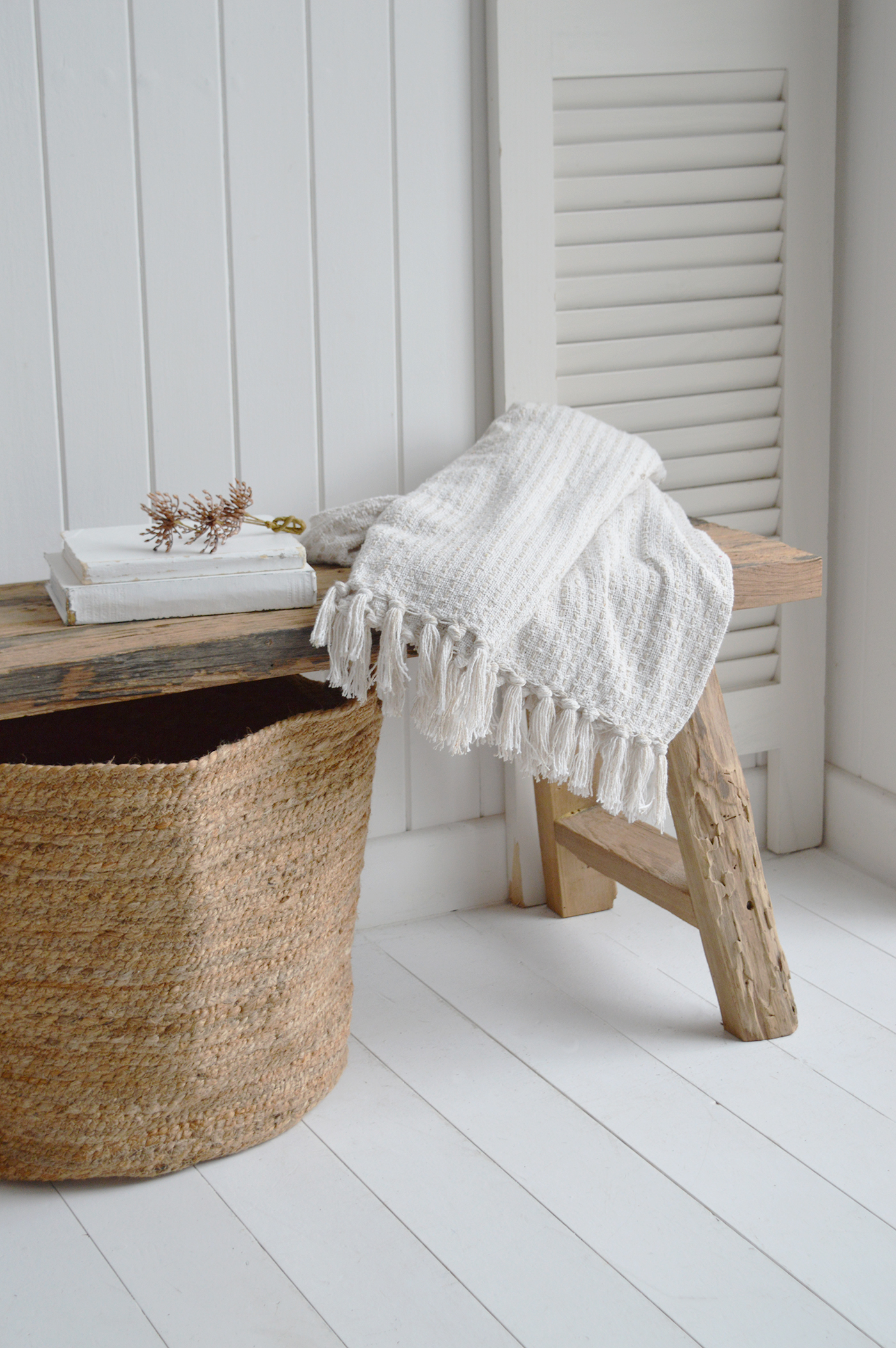 Styled with woven baskets beneath, a rustic wooden bench becomes a practical and decorative piece for coastal mudrooms.
